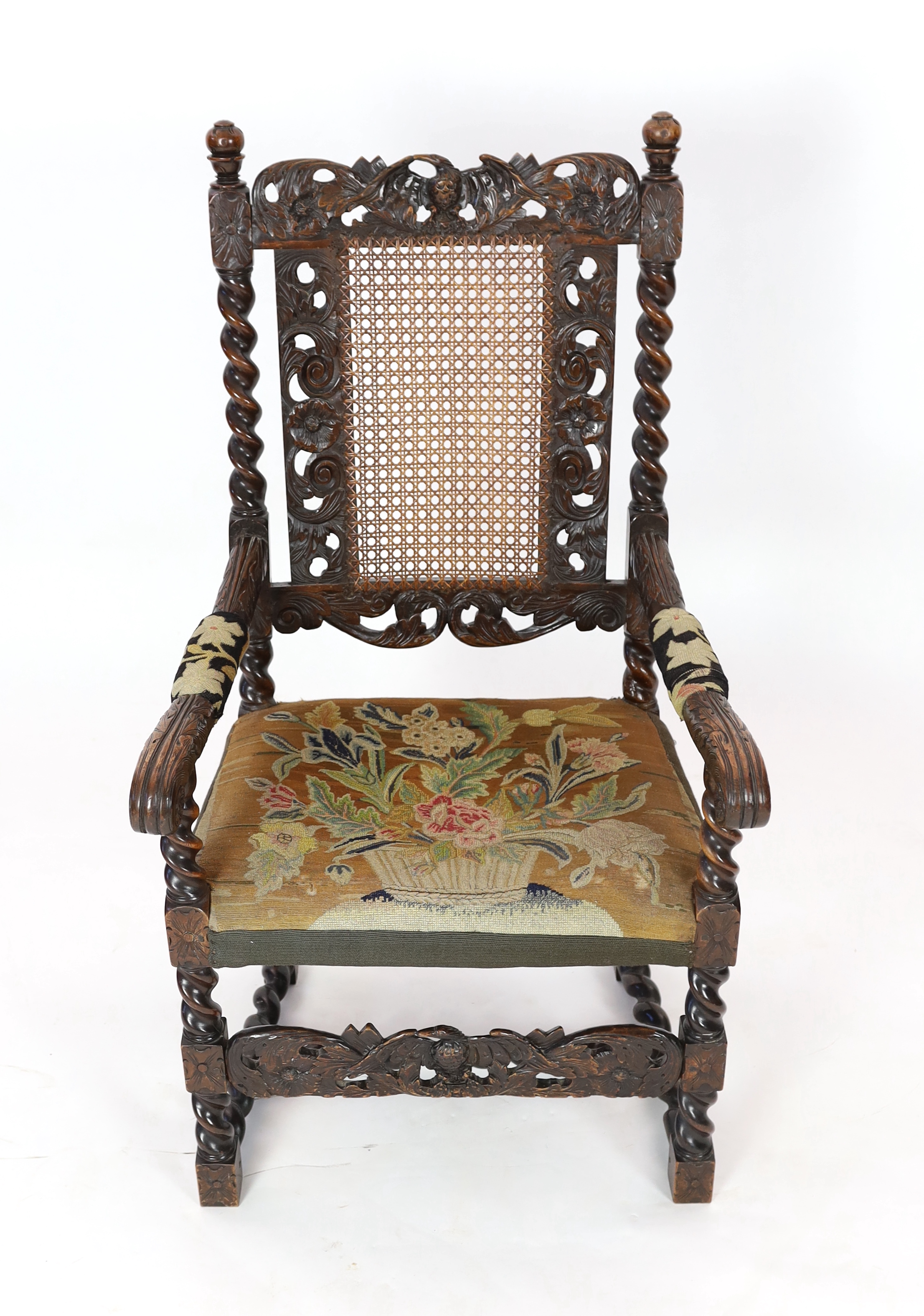 A Charles II carved walnut caned back elbow chair, with a contemporary needlework upholstered seat, c.1670, width 63cm, height 116cm, Please note this lot attracts an additional import tax of 5% on the hammer price